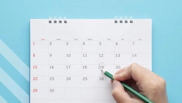 Calendar on blue background with hand recording a comment on a date