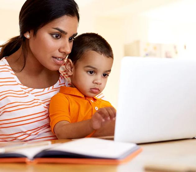 Mom sitting at a table with her son and a laptop