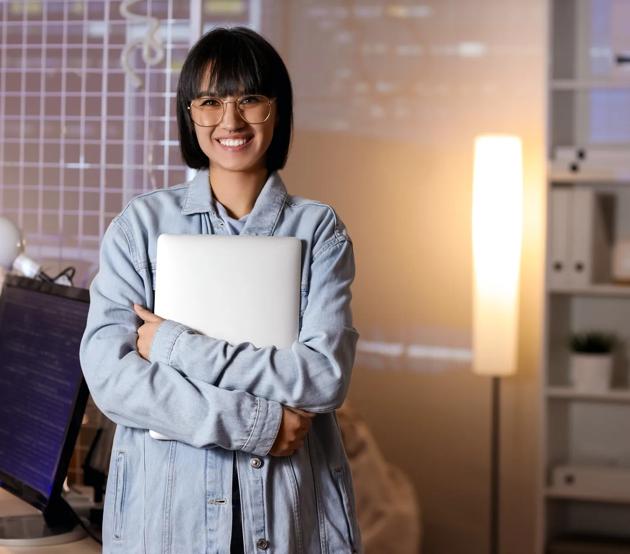Happy female programmer with laptop in office at night