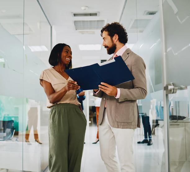 Business man and woman reviewing documents together in office hallway