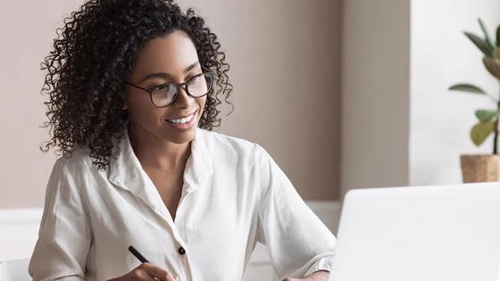 Student studying online on a laptop while taking notes.