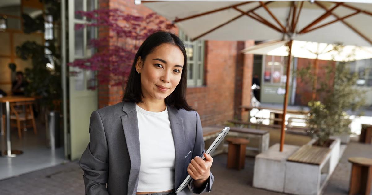 A young professional smiles for a portrait outside the office building where she works