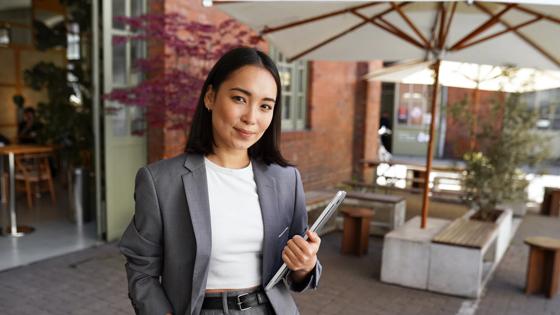 A young professional smiles for a portrait outside the office building where she works
