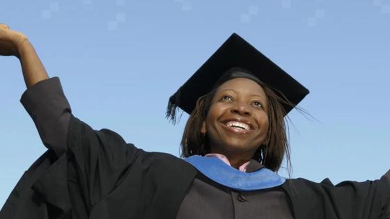A smiling African American woman wearing a graduation gown and hat