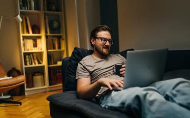 Caucasian man sitting on a sofa and using laptop.
