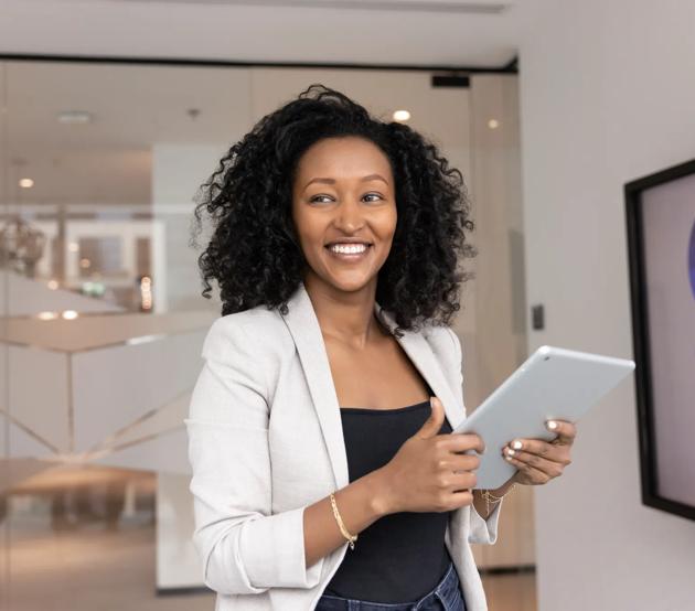 Smiling businesswoman looking aside distracted from using tablet in office