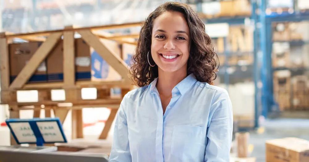 Woman working on a laptop in a warehouse setting.