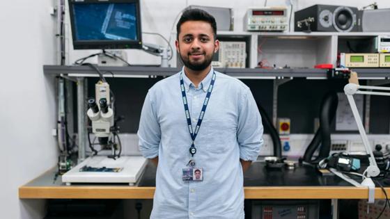 Engineering student standing in front of computers and lab equipment