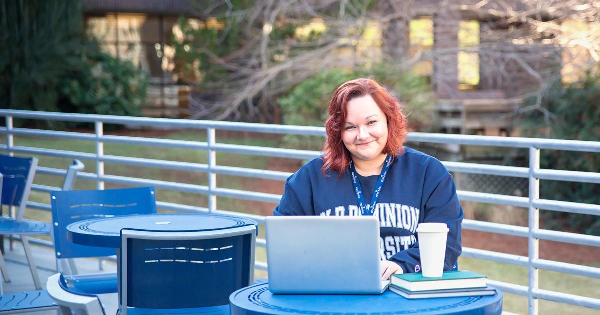 An Old Dominion University student smiles at the camera while seated outdoors.