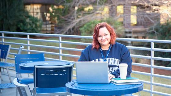 An Old Dominion University student smiles at the camera while seated outdoors.