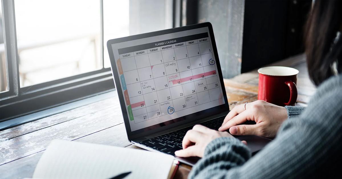 Student reviewing a calendar on a laptop while preparing for online classes.