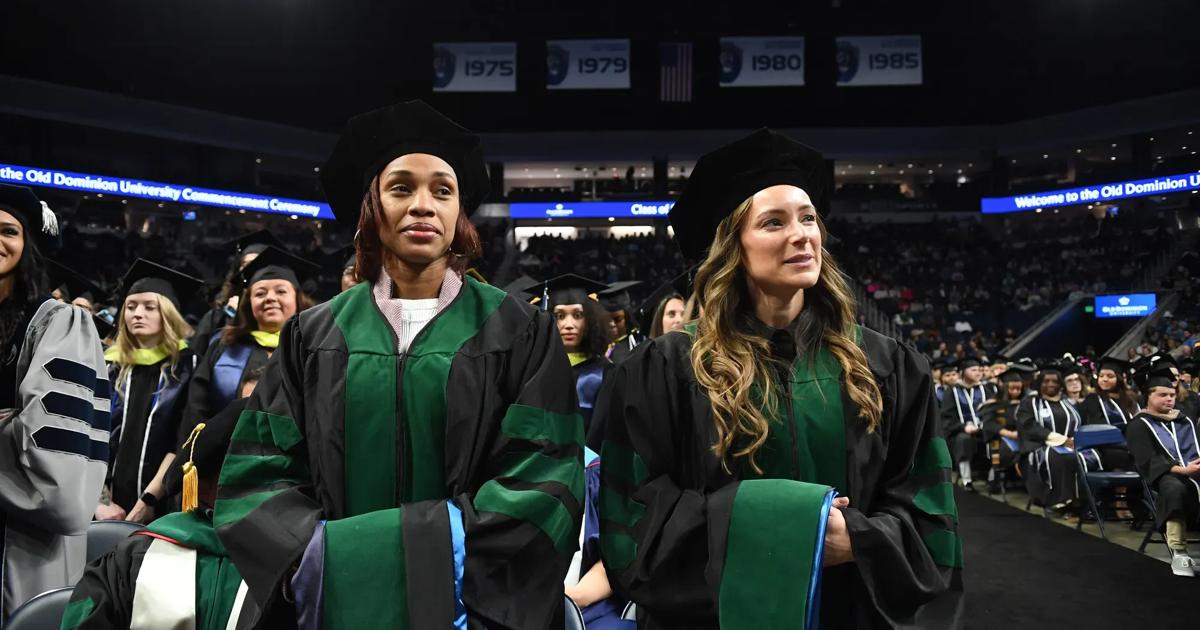 Two ODU graduate students stand ready to receive their degrees during the Commencement ceremony.