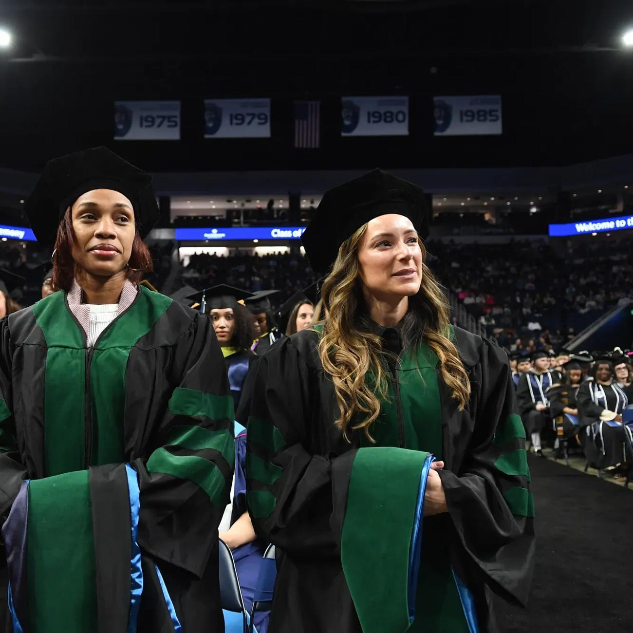 Two ODU graduate students stand ready to receive their degrees during the Commencement ceremony.
