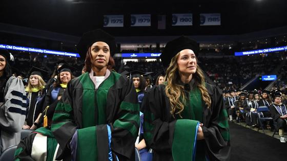 Two ODU graduate students stand ready to receive their degrees during the Commencement ceremony.