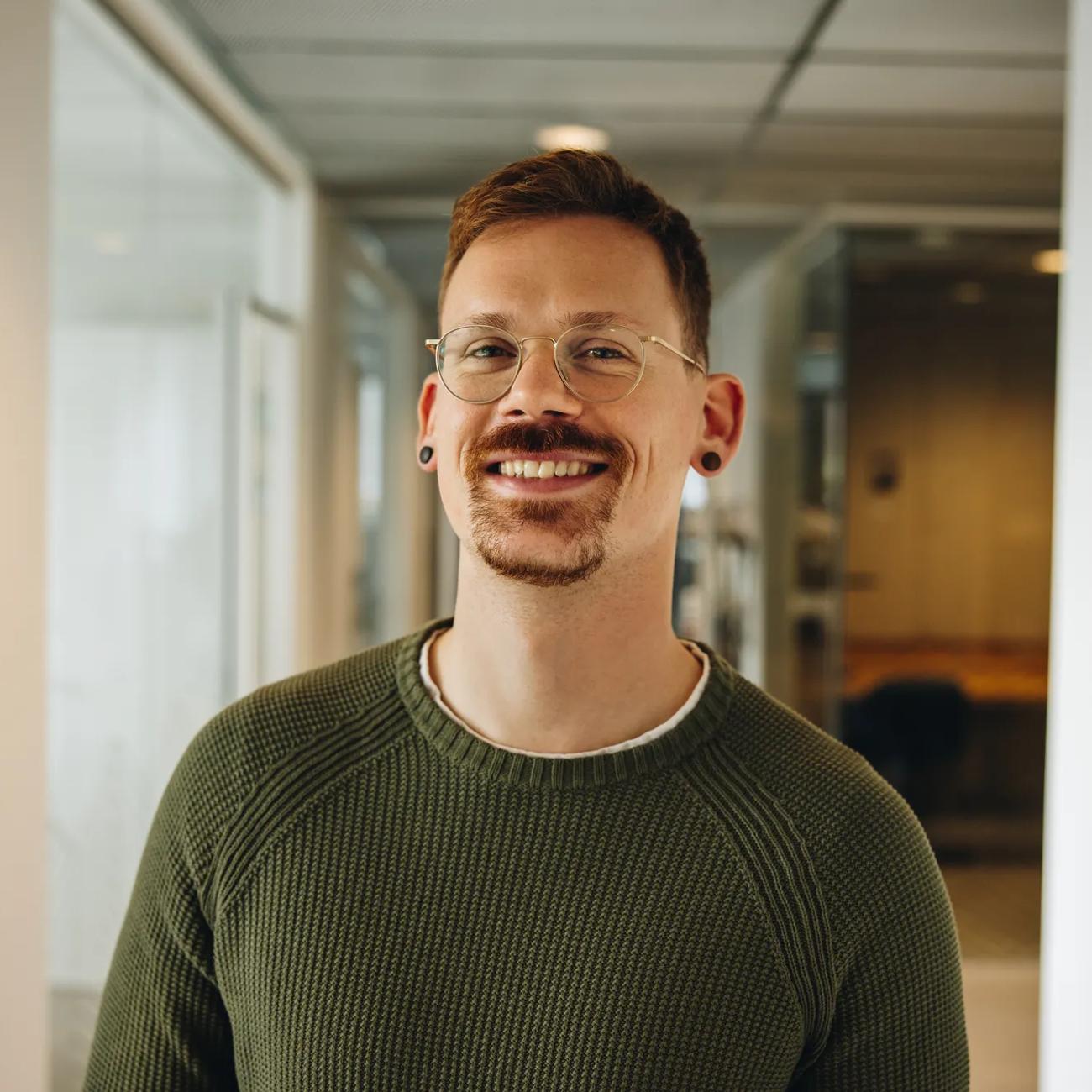 Portrait of smiling entrepreneur in office. Cheerful male executive in office corridor.