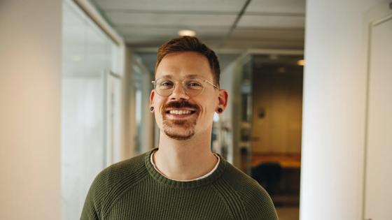 Portrait of smiling entrepreneur in office. Cheerful male executive in office corridor.