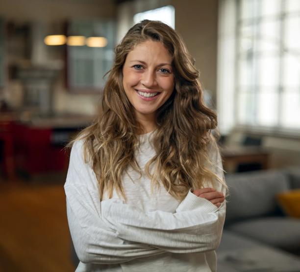 Authentic close up shot of an young attractive happy woman is smiling in camera in a living room at home.