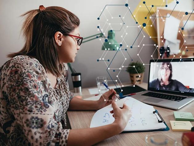 Woman seated at a desk with a laptop and notepaper for taking online chemistry courses.